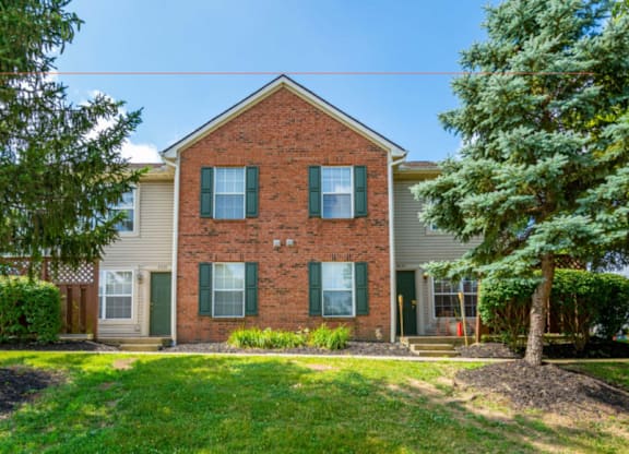 A red brick house with a green lawn in front.