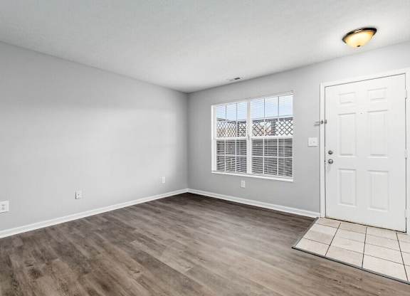 A room with a white door and a window with white blinds.