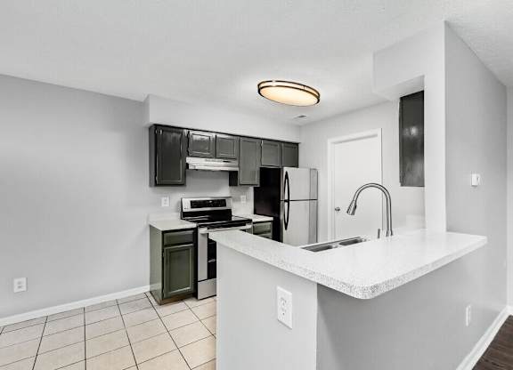 A kitchen with white countertops and black appliances.