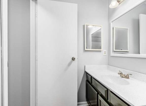 A white bathroom with a sink and mirror.