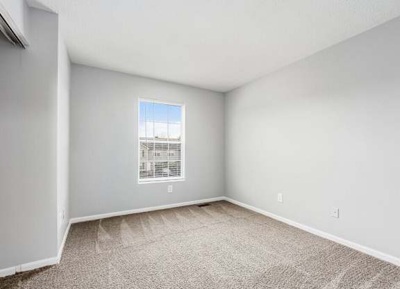 A room with a window and carpeted floor.