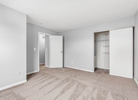A room with a carpeted floor and two open doors.