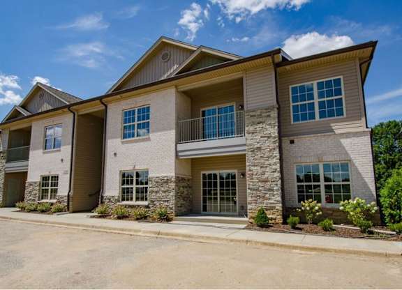 A large, modern house with a stone facade and a balcony.