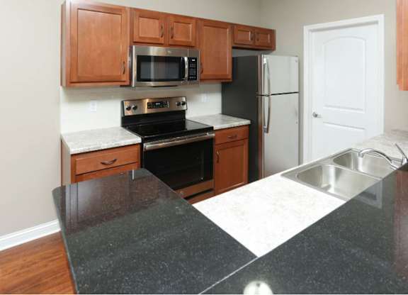A kitchen with a black counter top and wooden cabinets.