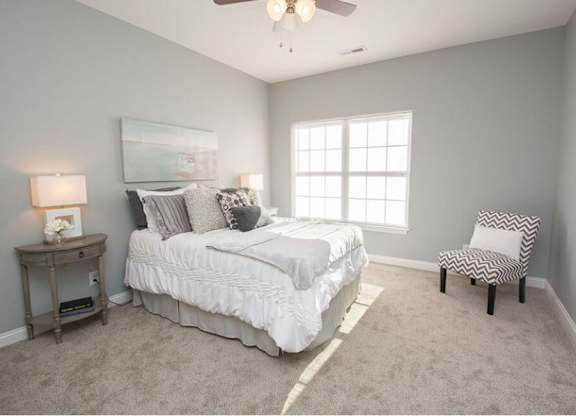 A bedroom with a bed, chair, and a painting on the wall.