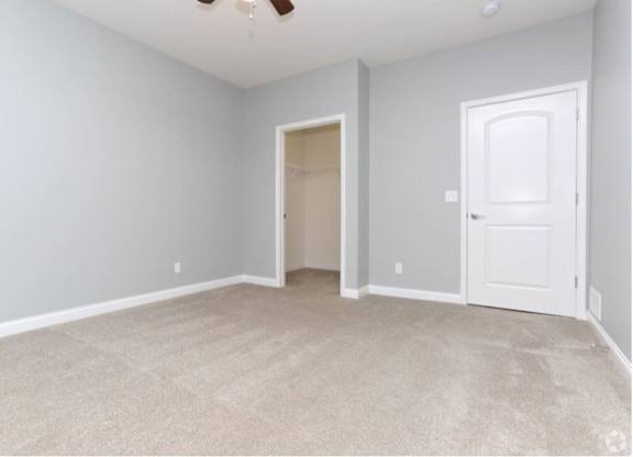A room with a carpeted floor and a ceiling fan.