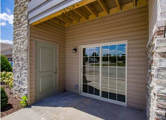 A house with a tan siding and a stone pillar.
