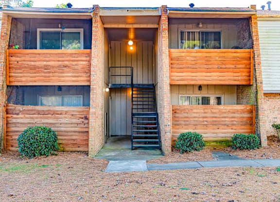 A two-story wooden house with a black staircase leading to the entrance.