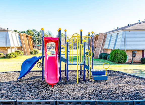 A playground with a red slide and a blue slide.