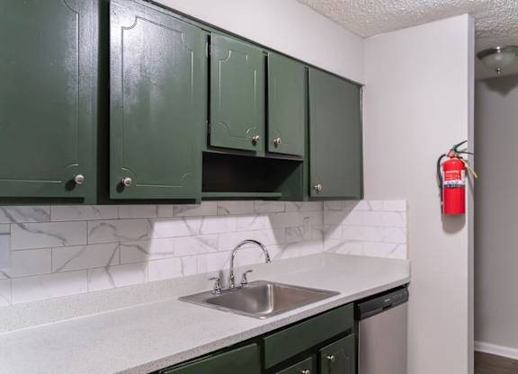 A kitchen with green cabinets and a white counter top.