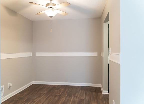 A room with a ceiling fan and wooden flooring.