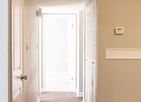 A long hallway with a door on the left and a window on the right.