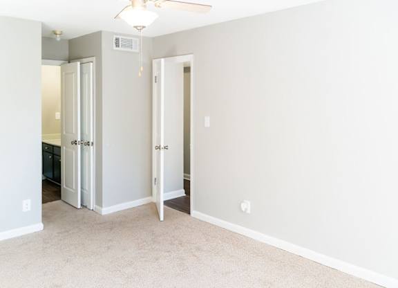 A room with a carpeted floor and a ceiling fan.