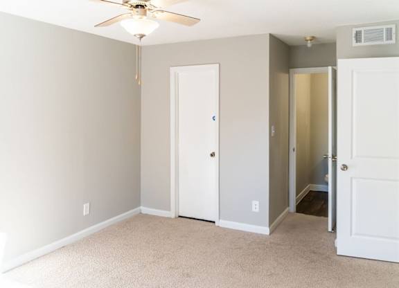 A room with a ceiling fan and two doors.