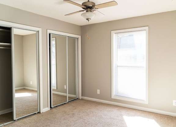 A room with a ceiling fan and a window.