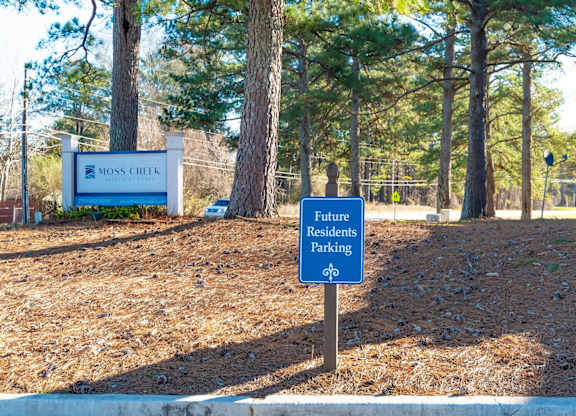 A sign for future residents parking stands in front of a Moss Creek sign.
