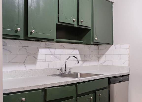 Green cabinets in a white tiled kitchen.