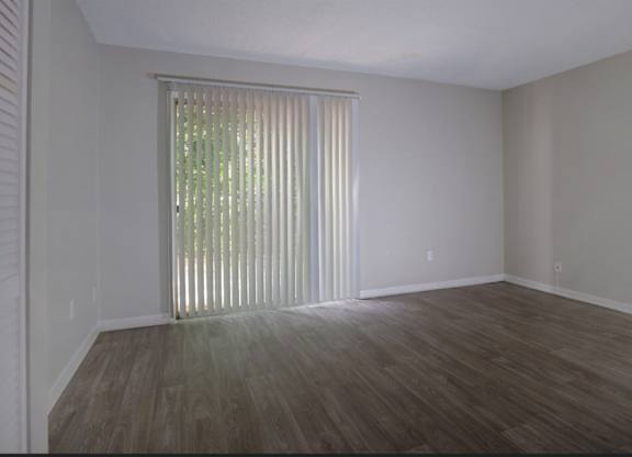A room with wooden flooring and a window with blinds.