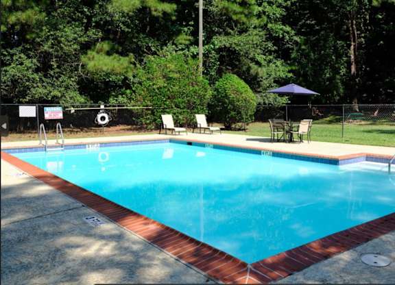 A rectangular pool with a red border and a blue umbrella.