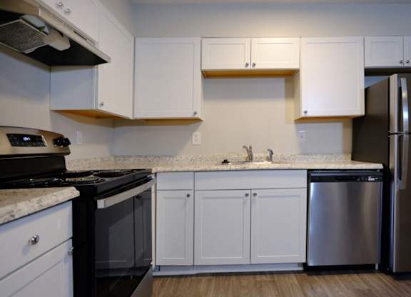 A kitchen with white cabinets and a black stove top oven.