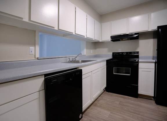 A kitchen with black appliances and white cabinets.