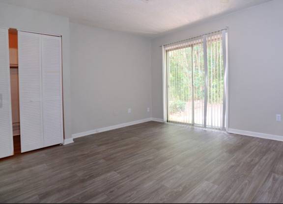 A room with wooden flooring and a sliding glass door.