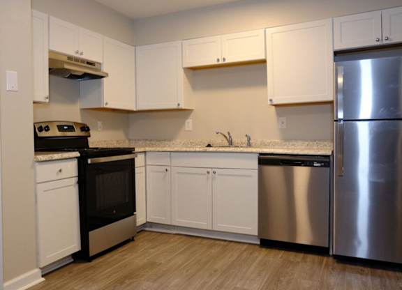 A kitchen with white cabinets and a stainless steel refrigerator.
