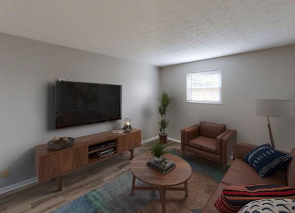 A living room with a brown couch, a wooden coffee table, and a flat screen TV mounted on the wall.