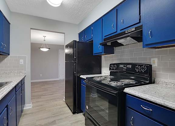 A kitchen with blue cabinets and black appliances.