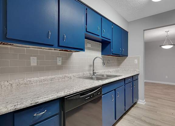A kitchen with blue cabinets and a marble countertop.