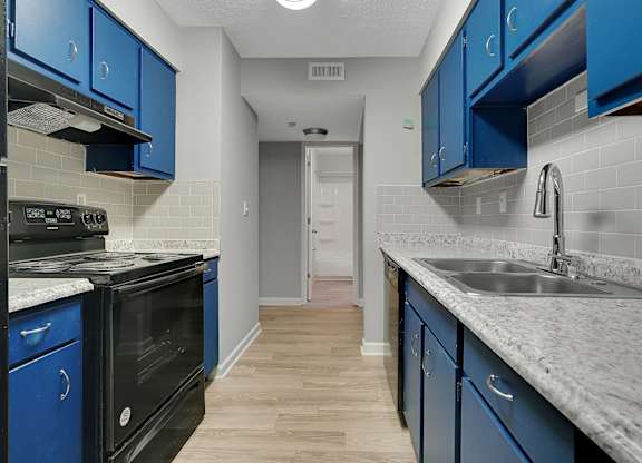 A kitchen with blue cabinets and a black oven.