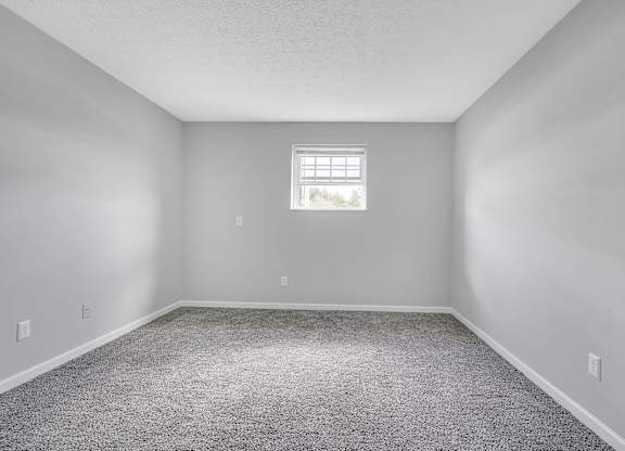 A room with a carpeted floor and a window.