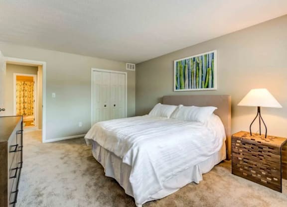 A bedroom with a large bed and a wooden nightstand.