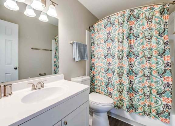 A bathroom with a floral shower curtain and a white toilet.