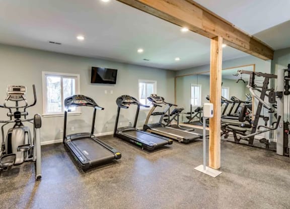 A home gym with a variety of exercise equipment including treadmills, elliptical machines, and a stationary bike.