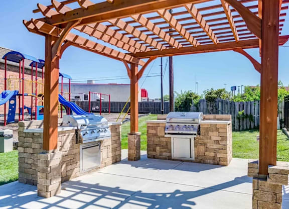 A playground with a wooden pergola and a slide in the background.