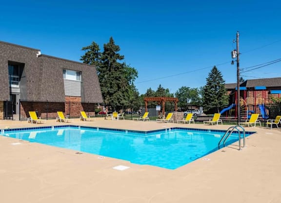 A large swimming pool with yellow chairs around it.