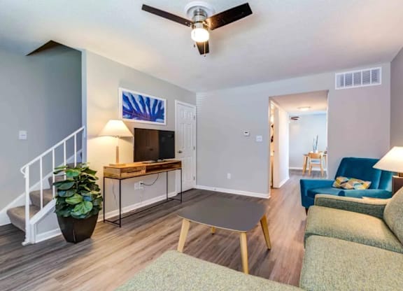 A living room with a couch, a coffee table, and a ceiling fan.