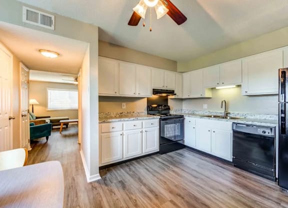 A kitchen with white cabinets and a black refrigerator.