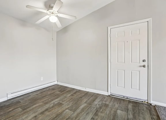 A room with a white door and a ceiling fan.