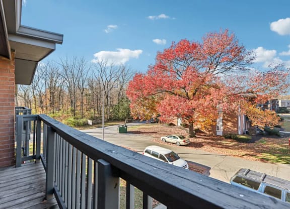 A balcony overlooks a parking lot with cars and trees.