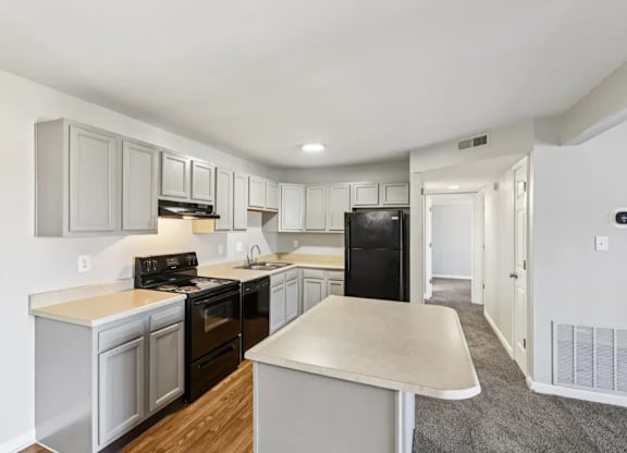 A kitchen with white cabinets and a black fridge.
