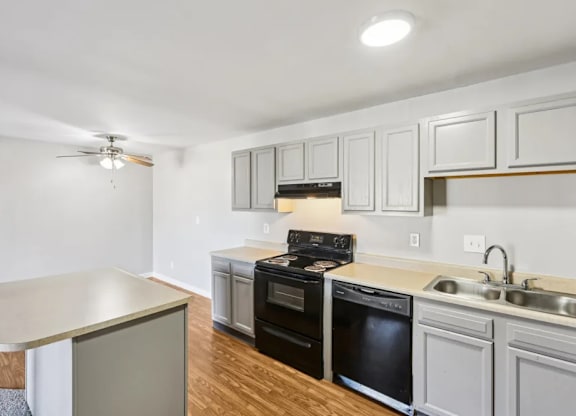 A kitchen with a black stove top oven and white cabinets.