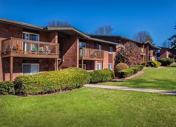 Apartment complex with green lawn and trees.