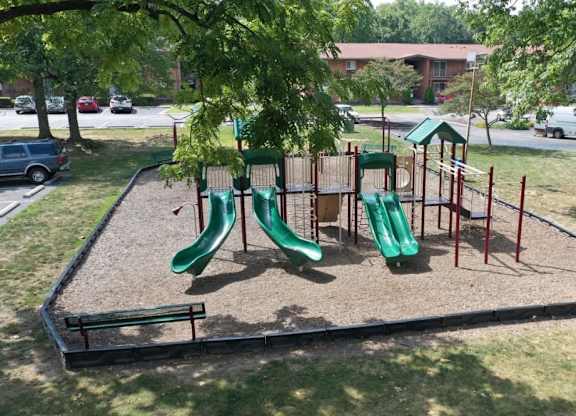 A playground with a green slide and a red and green play structure.