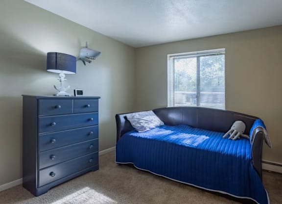 A bedroom with a blue bed and a dresser.