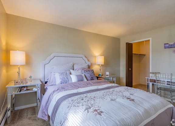 A bedroom with a large bed and a nightstand with a lamp.