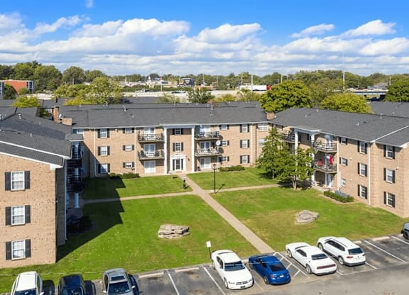 A sunny day at a residential complex with cars parked in the lot.