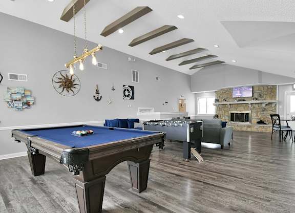 A pool table is in the middle of a room with a fireplace and a TV.