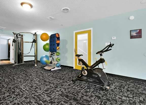 A room with a treadmill, exercise balls, and a yellow door.